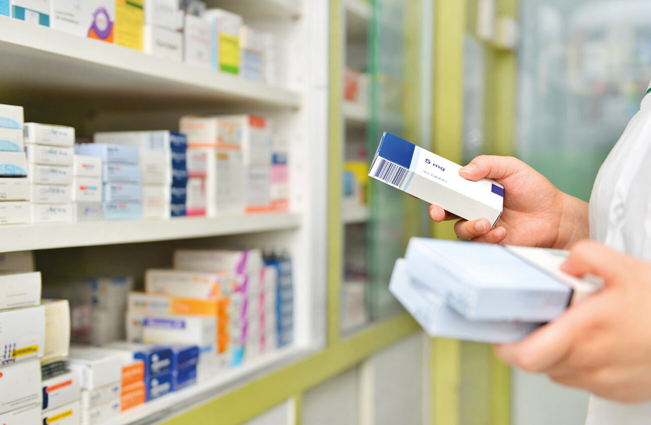 Pharmacist holding medicine box in pharmacy drugstore.