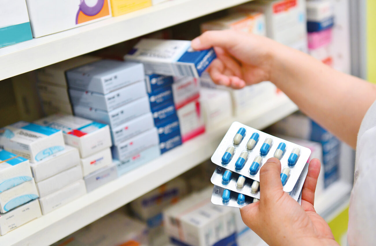 Pharmacist holding medicine box and capsule pack in pharmacy dru